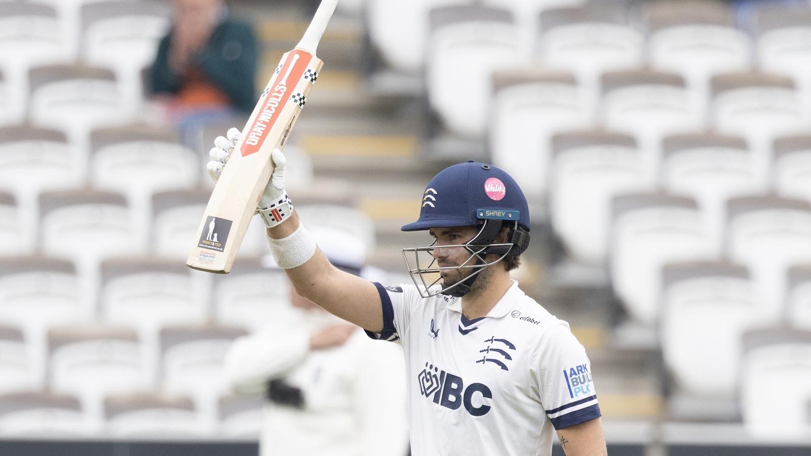 Middlesex's Max Holden raises his bat after scoring a century against Durham